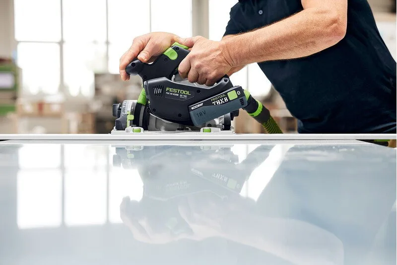 A woodworker using the TSC 55 KS on a guide rail across a panel