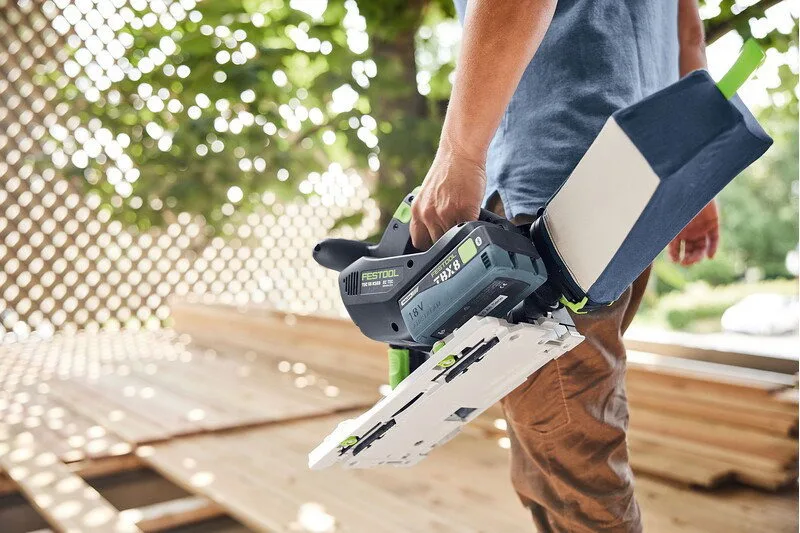 A carpenter carrying the TSC 55 KS and a guide rail outdoors