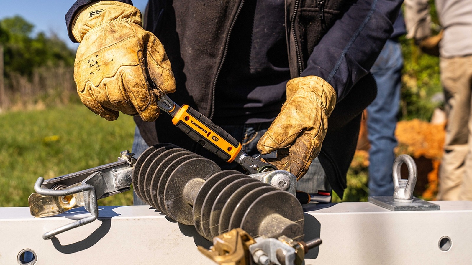 Lineman in work gloves using a GEARWRENCH tool on utility hardware