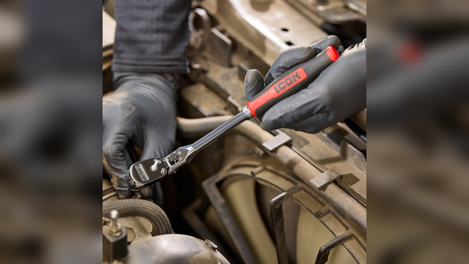 Mechanic using an ICON G2 ratchet with a red comfort grip on a fastener inside an engine bay
