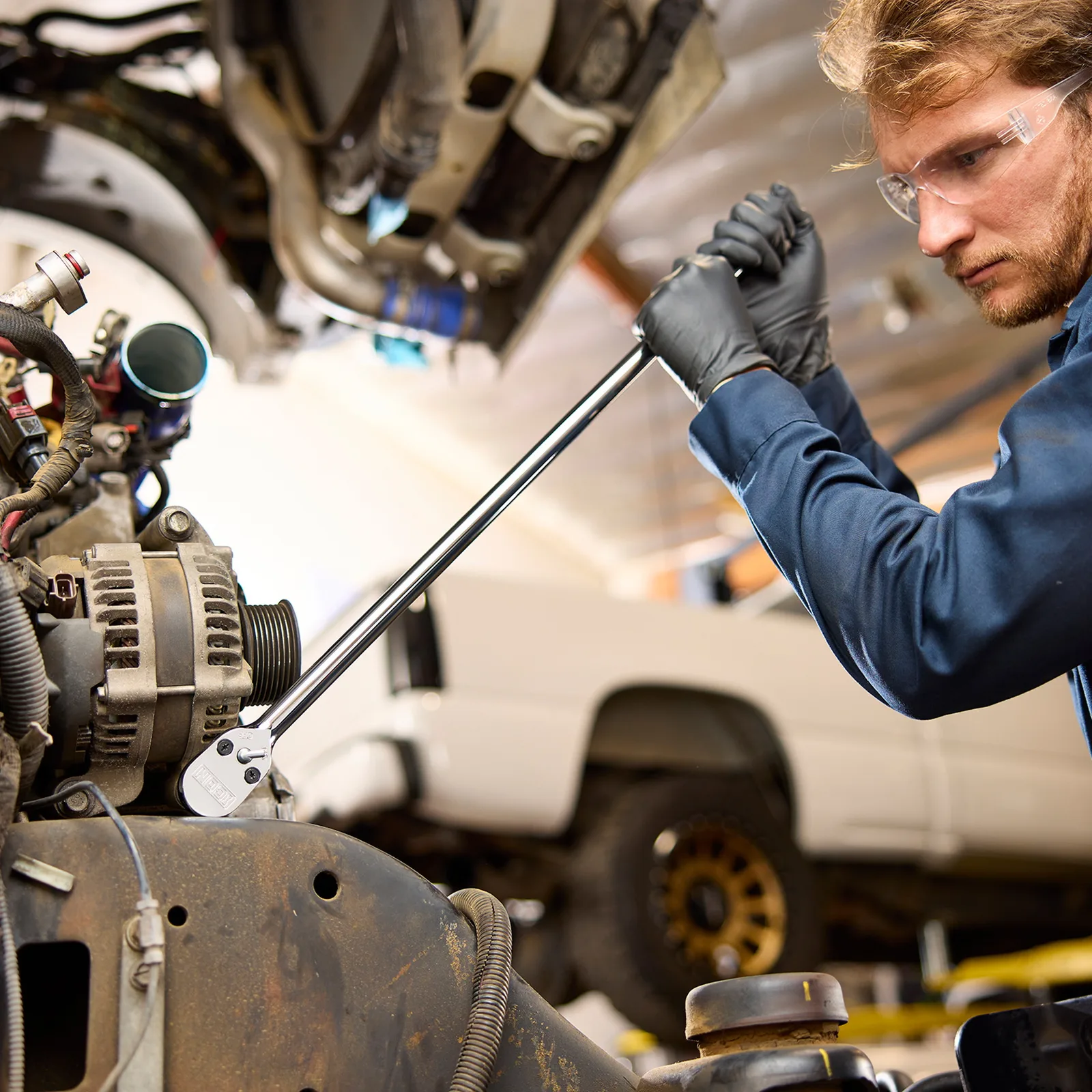 A mechanic leaning on a long ICON G2 ratchet to break a stubborn bolt loose