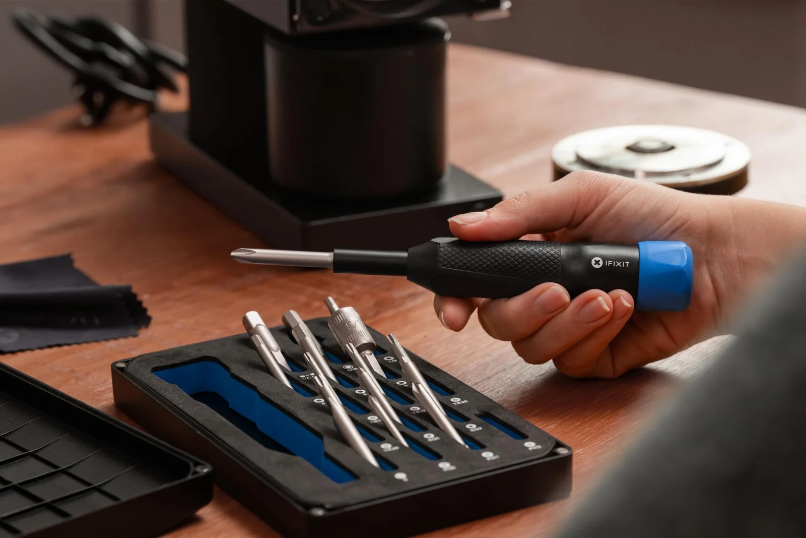 A hand using the driver next to its open case