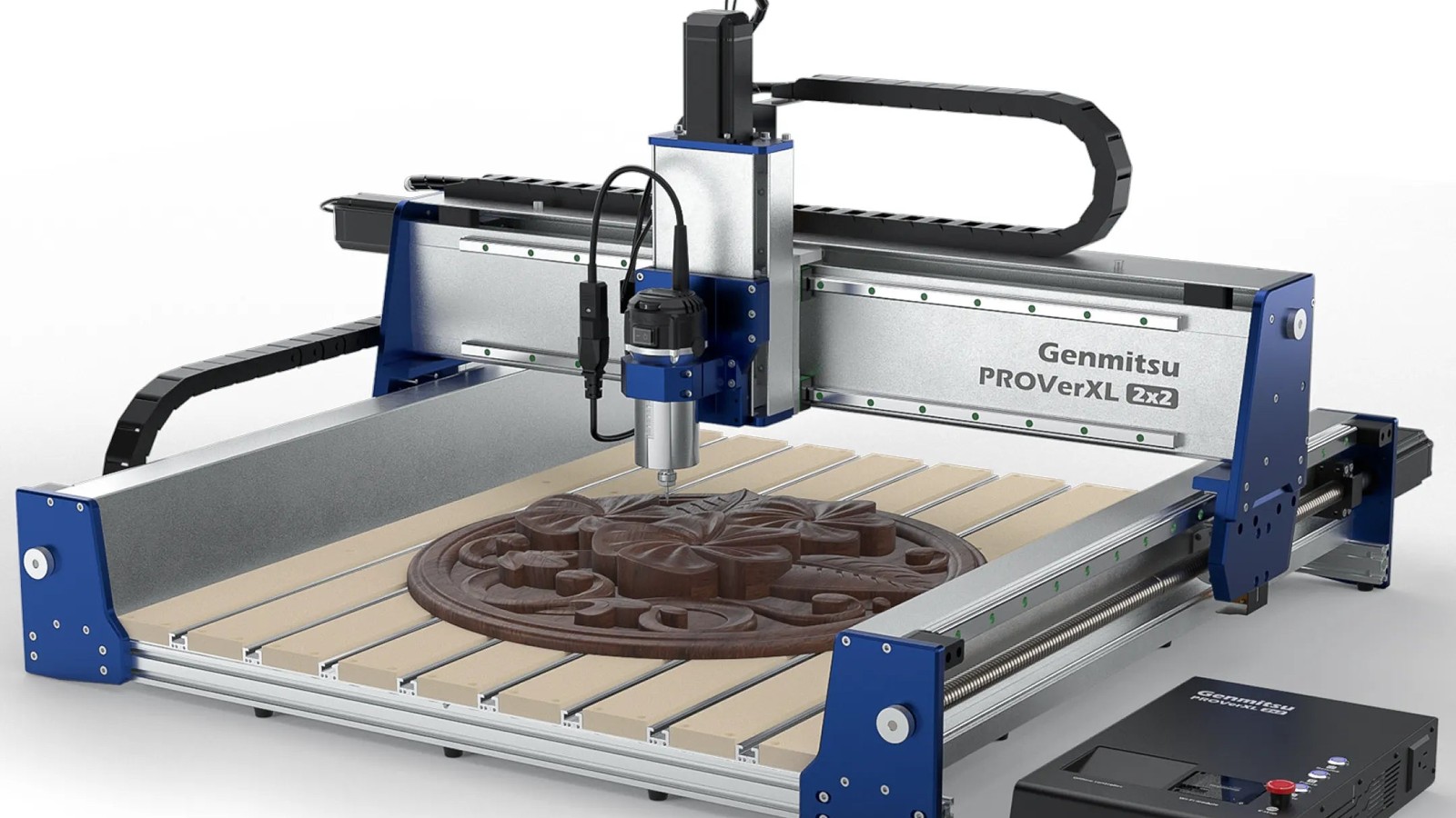 Fully assembled Genmitsu PROVerXL 2×2 CNC router with a blue and silver frame, a spindle above a slatted table holding a carved round relief, and the controller box at the front right