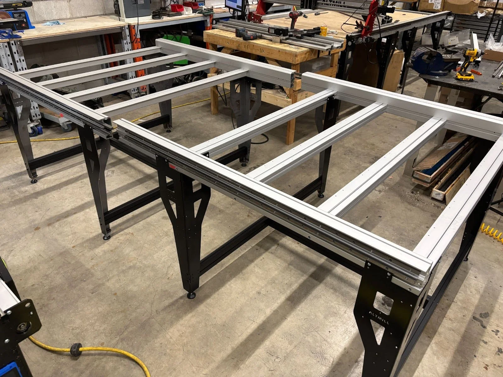 The AltMill 4×8's black steel frame and aluminum table assembled in a shop