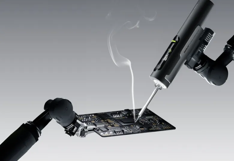 Hoto Snapbloq I-A06 cordless soldering iron working on a circuit board with a wisp of flux smoke