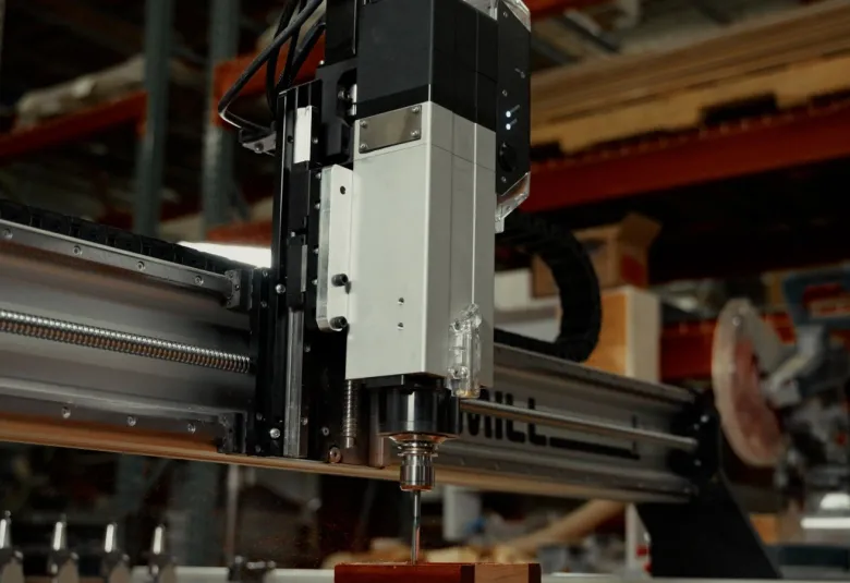 Sienci AltMill automatic tool changer spindle cutting a block of wood in a workshop, with the tool rack visible at the left