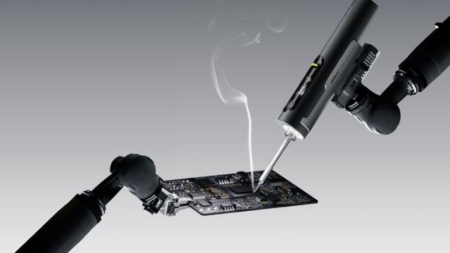 Hoto Snapbloq I-A06 cordless soldering iron working on a circuit board with a wisp of flux smoke