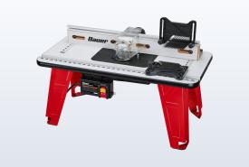 Red-legged BAUER benchtop router table with a router mounted underneath and a clear bit guard
