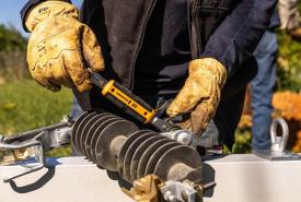 Lineman in work gloves using a GEARWRENCH tool on utility hardware