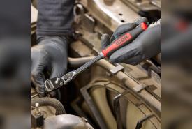 Mechanic using an ICON G2 ratchet with a red comfort grip on a fastener inside an engine bay