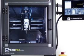 Tormach xsTECH Pro enclosed CNC router with a glass door, a spindle visible inside, and a touchscreen on an arm at the right