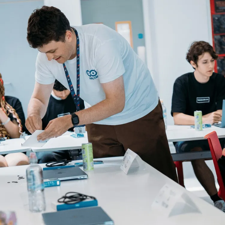 People gathered around a table with Arduino boards at an Arduino community event
