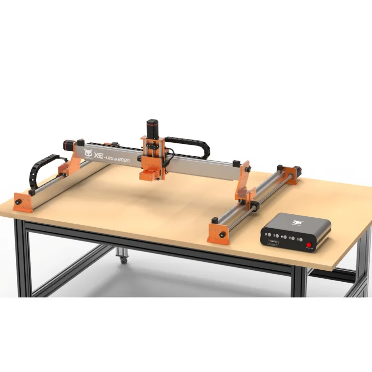 FoxAlien XE-Ultra 8080 CNC router with orange brackets and black drag chains mounted on a workbench, controller box sitting on the table beside it