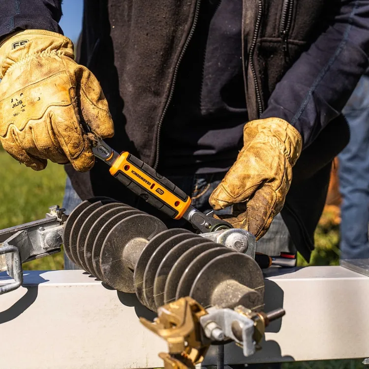 Lineman in work gloves using a GEARWRENCH tool on utility hardware