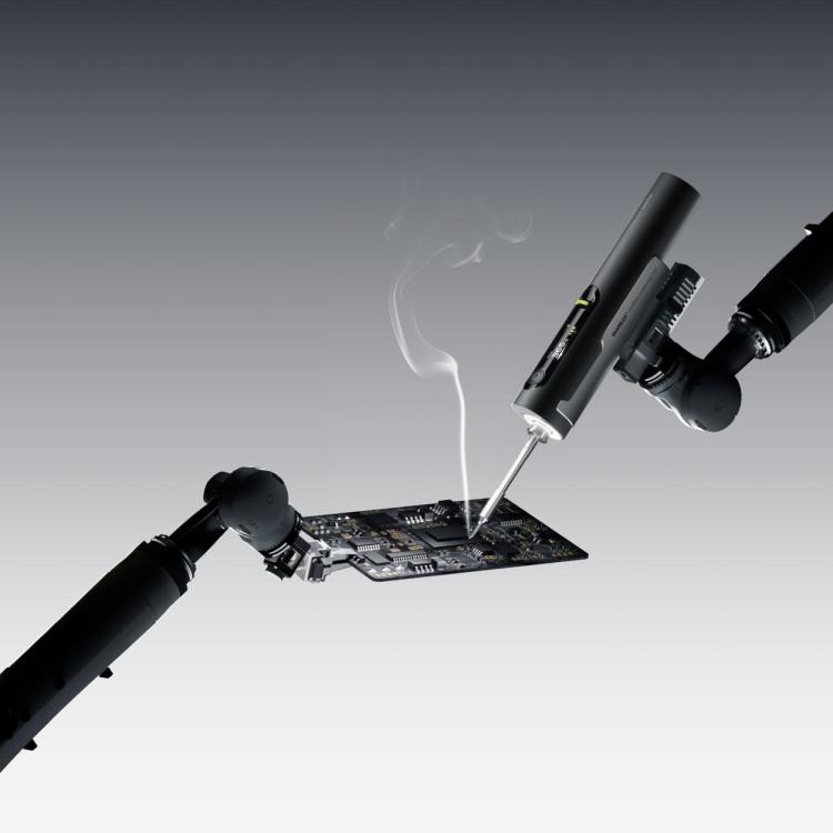 Hoto Snapbloq I-A06 cordless soldering iron working on a circuit board with a wisp of flux smoke