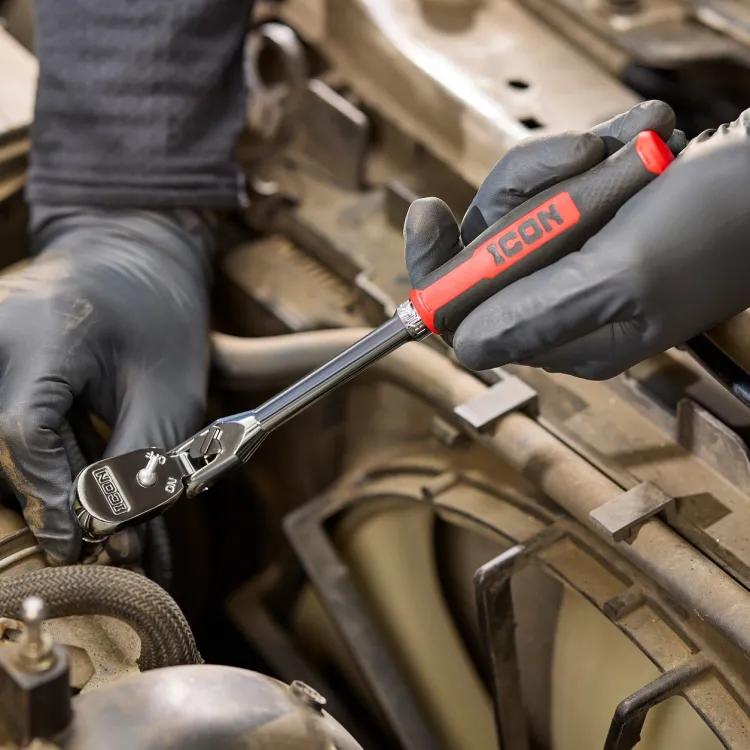 Mechanic using an ICON G2 ratchet with a red comfort grip on a fastener inside an engine bay