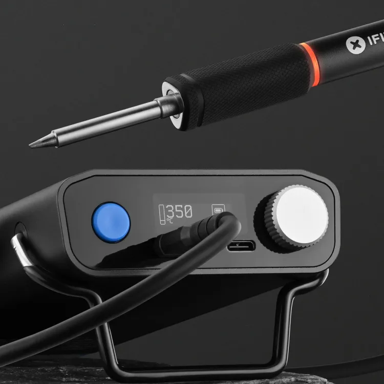 iFixit FixHub smart soldering iron resting beside its portable power station on a dark background
