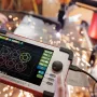Hands holding the ArcDroid Plus controller with a touchscreen showing circle cut paths and a joystick, with plasma cutting sparks in the background