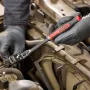 Mechanic using an ICON G2 ratchet with a red comfort grip on a fastener inside an engine bay