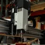 Sienci AltMill automatic tool changer spindle cutting a block of wood in a workshop, with the tool rack visible at the left